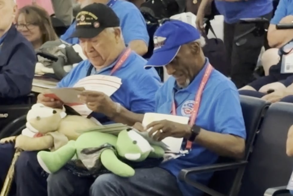 Veterans look at letters and hold teddy bears.