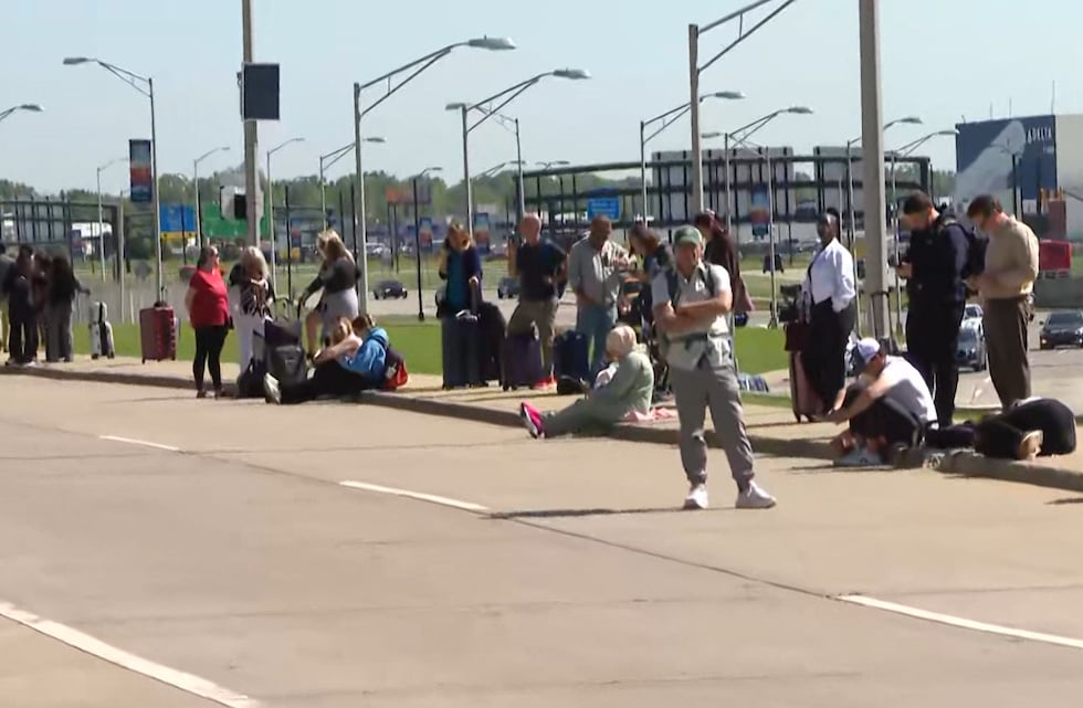 Travelers wait outside Detroit Metro Airport after crash closes Evans Terminal
